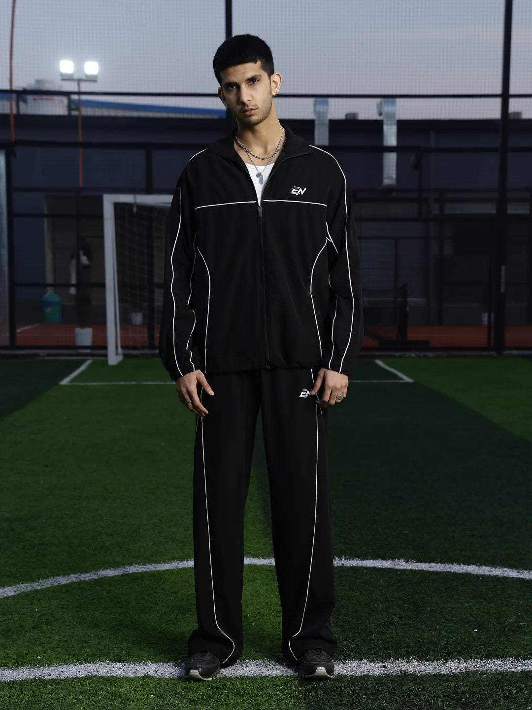 Man wearing a black sports jacket  with a logo on a sports field