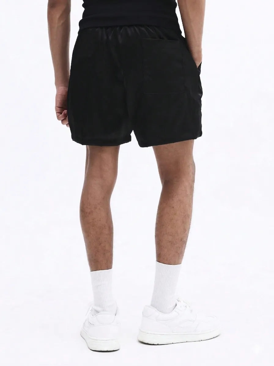Black shorts with white stripes worn by a person on a plain background