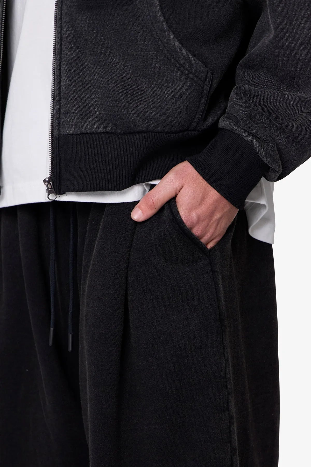 Person wearing black baggy sweatpants with a plain background