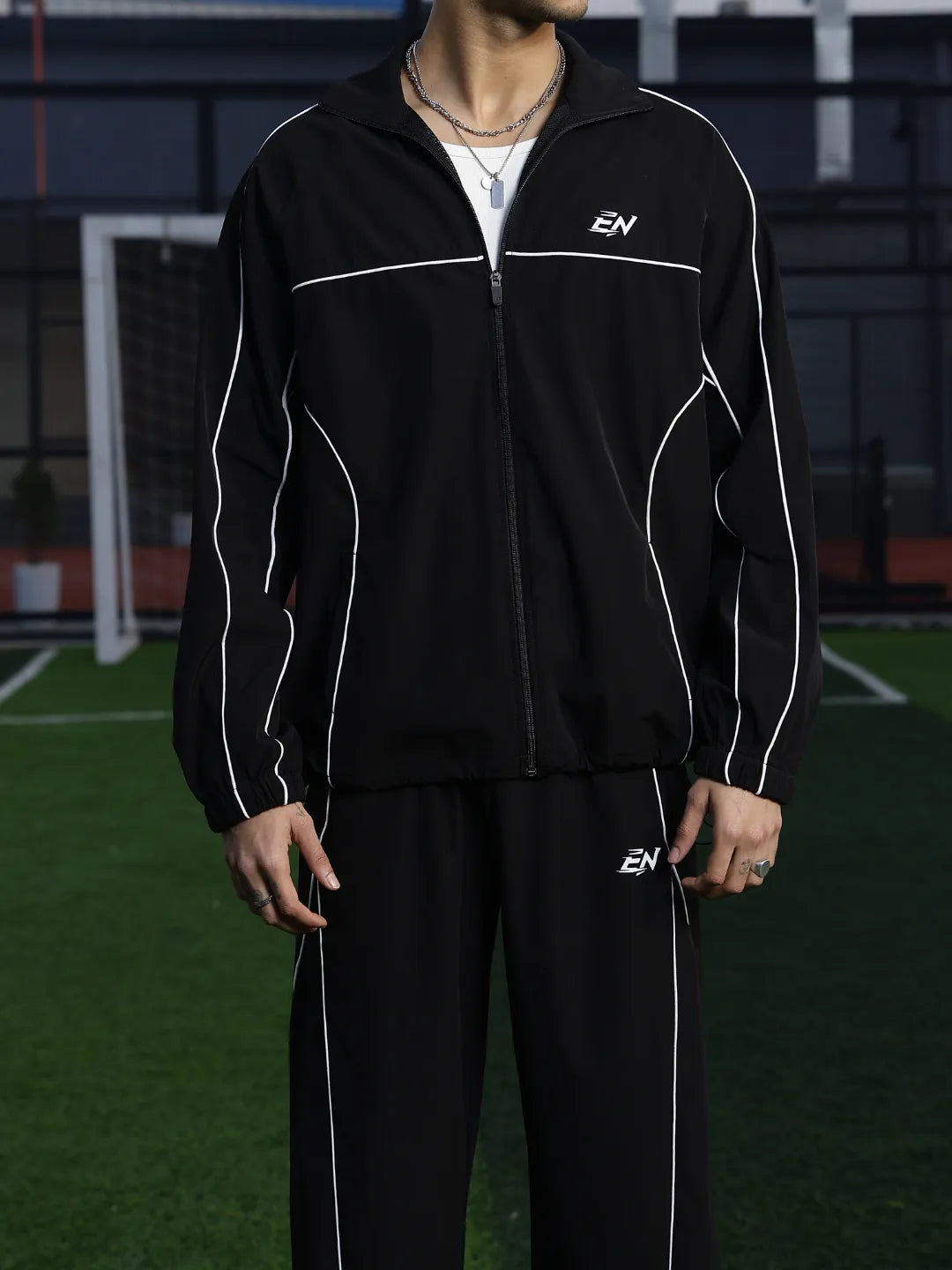 Person wearing a black tracksuit with white accents on a sports field