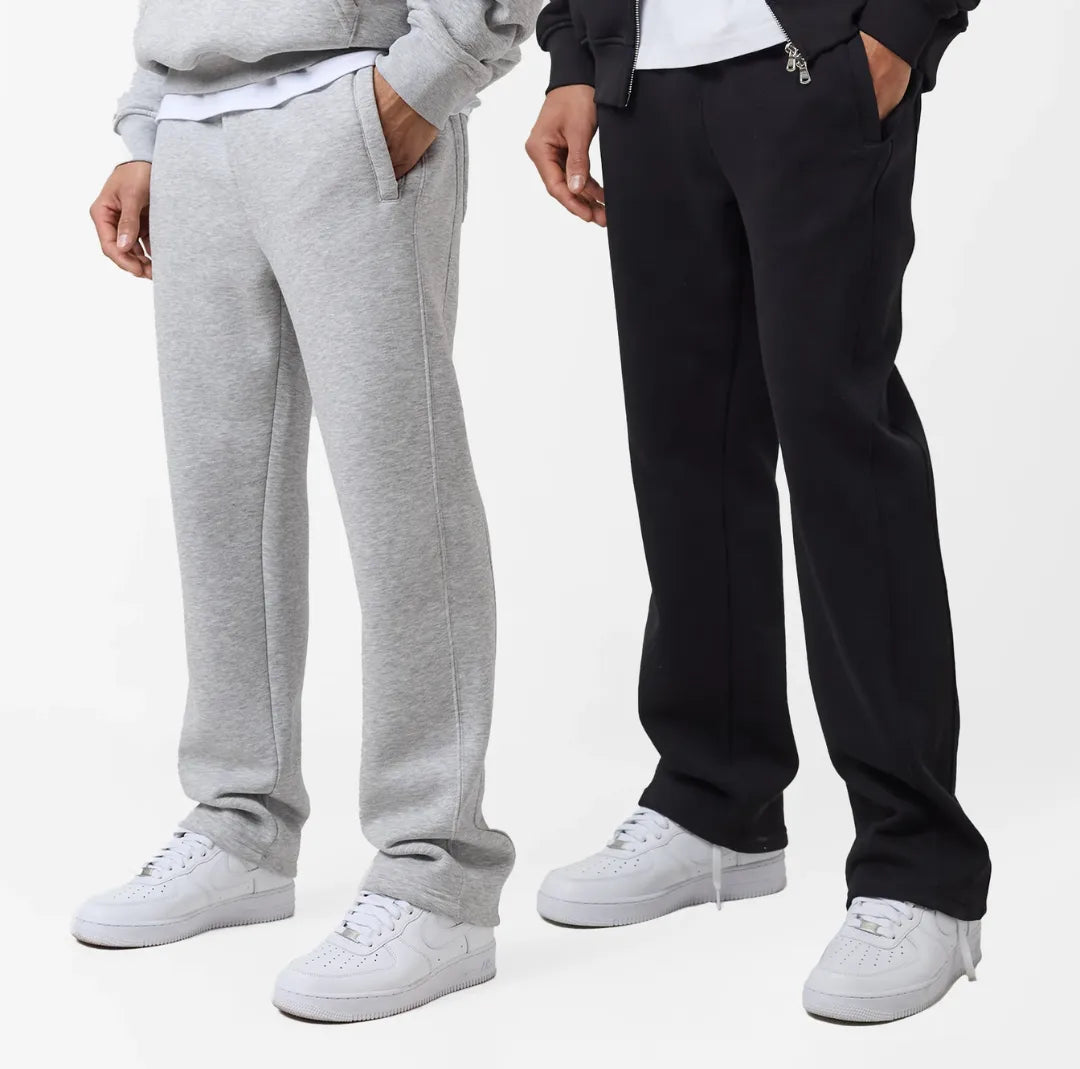 Two pairs of joggers, one grey and one black, worn by people on a white background.