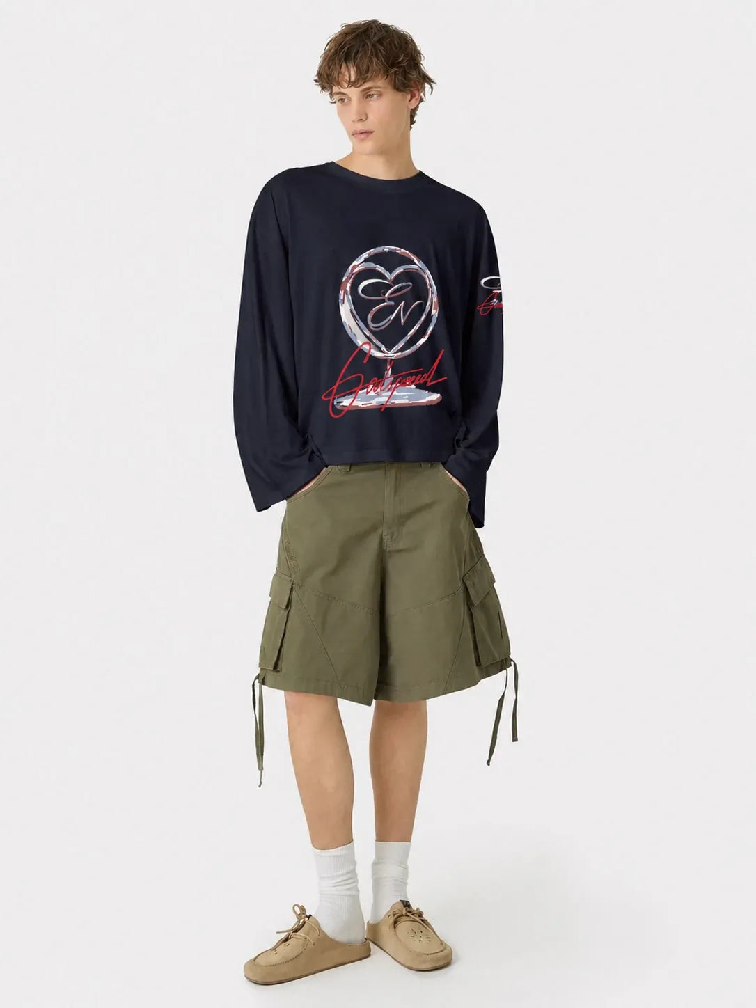 Person wearing a dark blue oversized t-shirt with a graphic design and green shorts on a white background