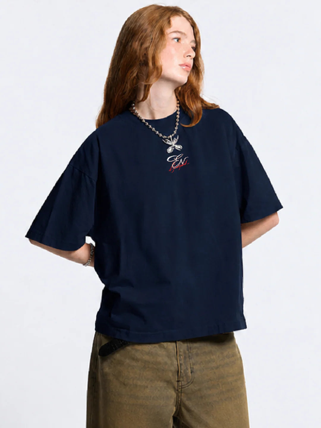 Person wearing a navy blue oversized t-shirt with a logo on a white background