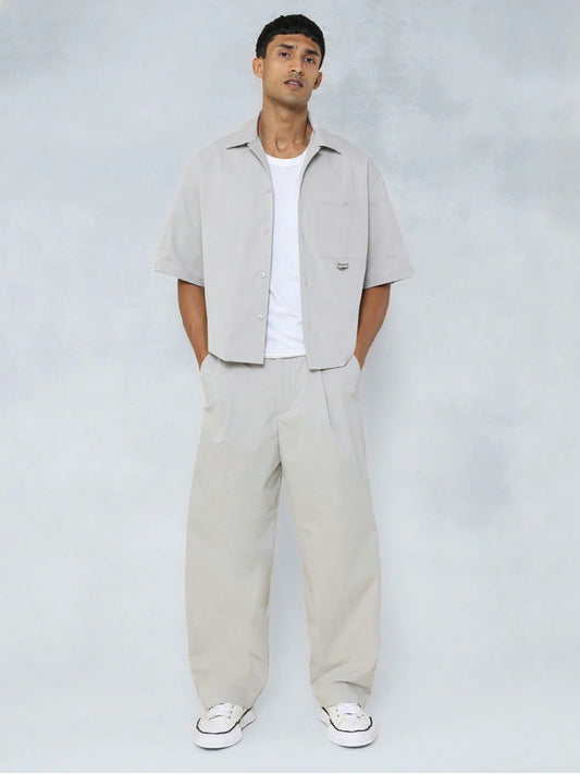 Man wearing a beige shirt and pants with a white background