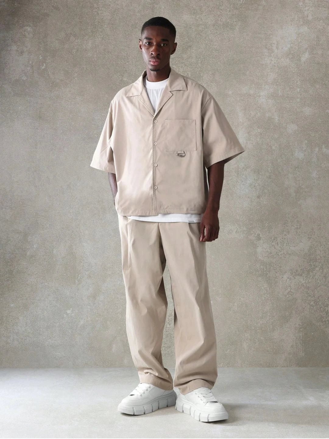 Person wearing a beige outfit with a plain background