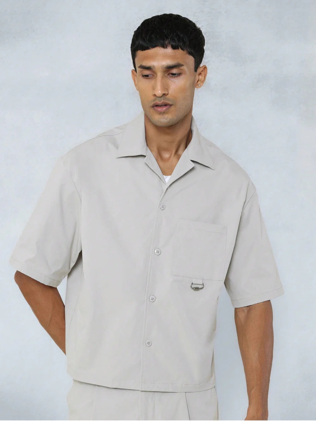 Man wearing a beige short-sleeve shirt against a plain background