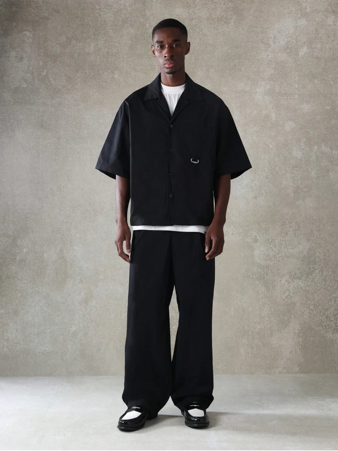 Man wearing a black outfit against a plain background
