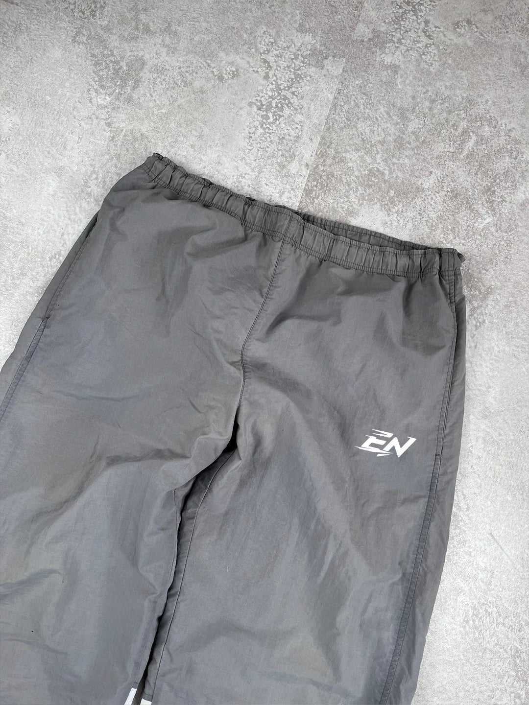 Grey pants with a brand logo on a grey concrete surface