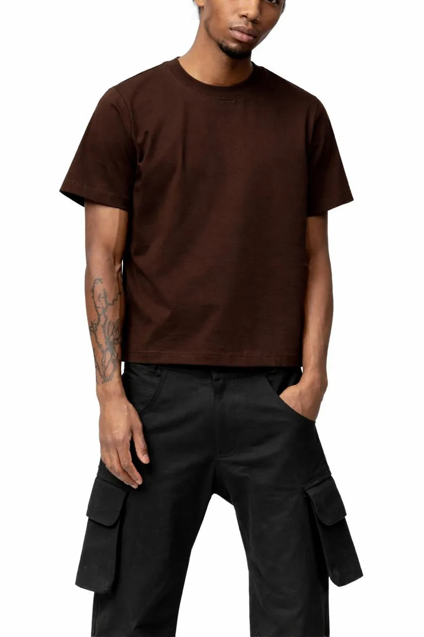 Man wearing a brown t-shirt and black cargo pants on a white background