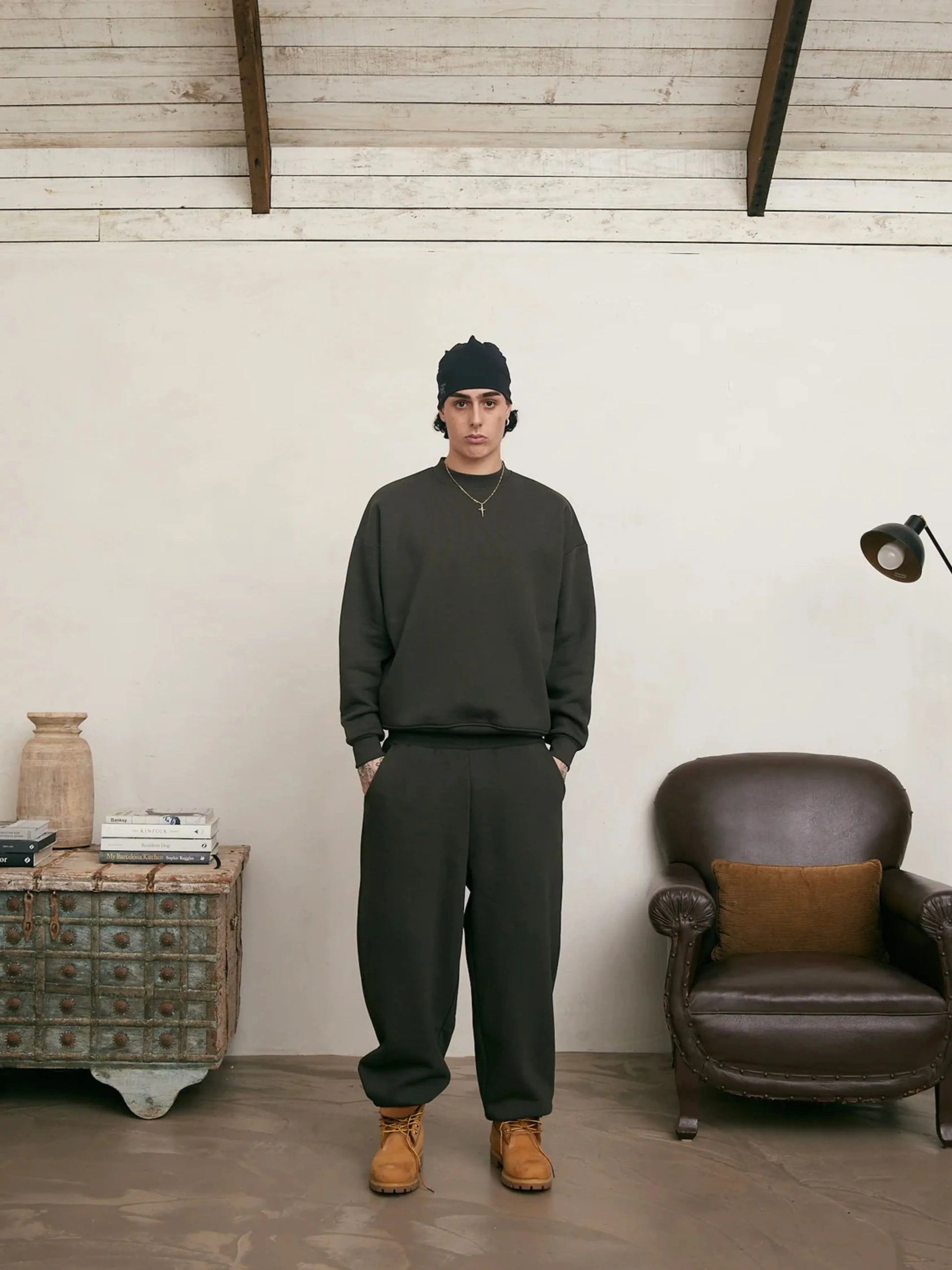 Person wearing a coffee sweatshirt and sweatpants set standing in a room with a wooden floor and white walls.