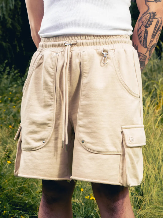 Beige shorts worn by a person in a natural setting with greenery.