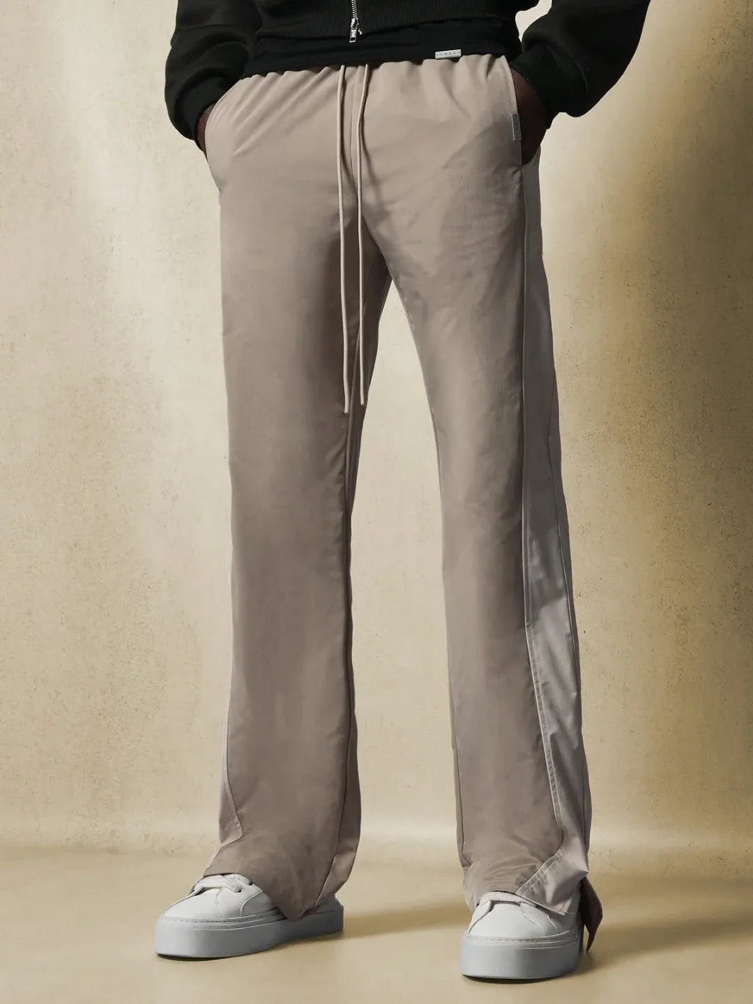 Beige pants with a side stripe worn by a person on a beige background