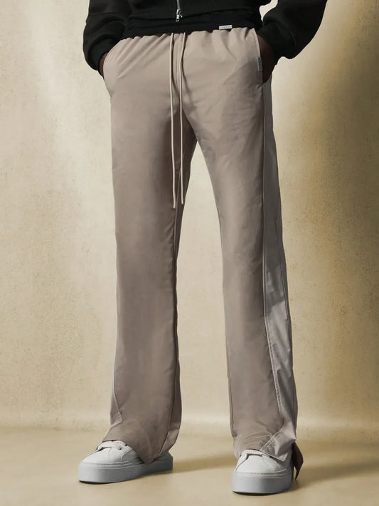 Beige pants with a side stripe worn by a person on a beige background