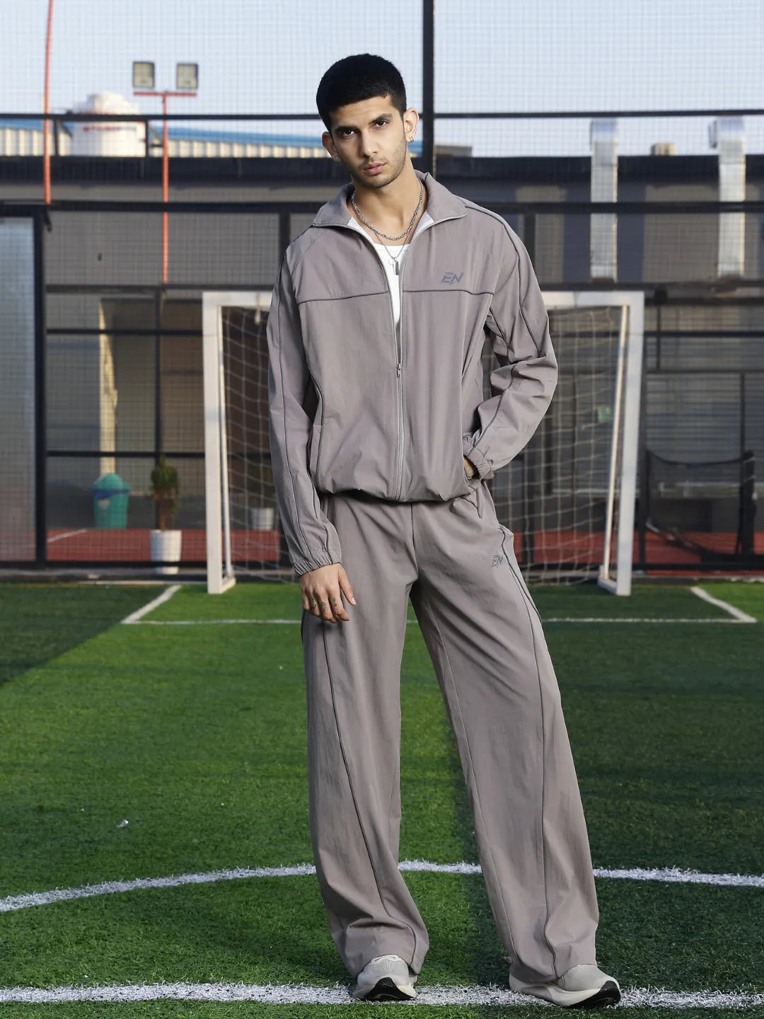 Man wearing a grey tracksuit on a sports field