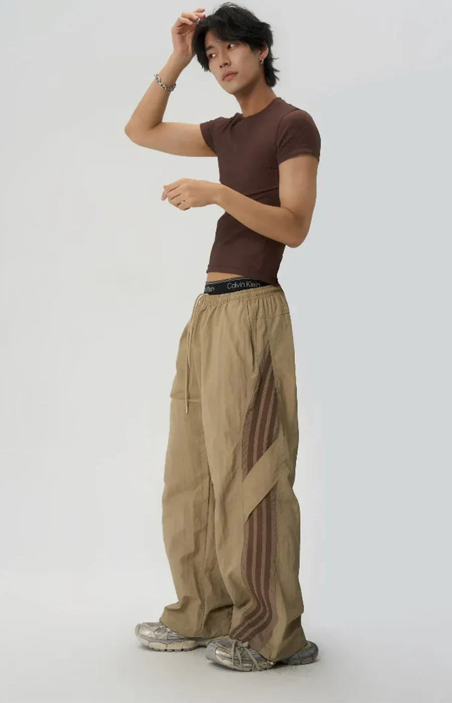 Person wearing a brown t-shirt and beige pants on a white background