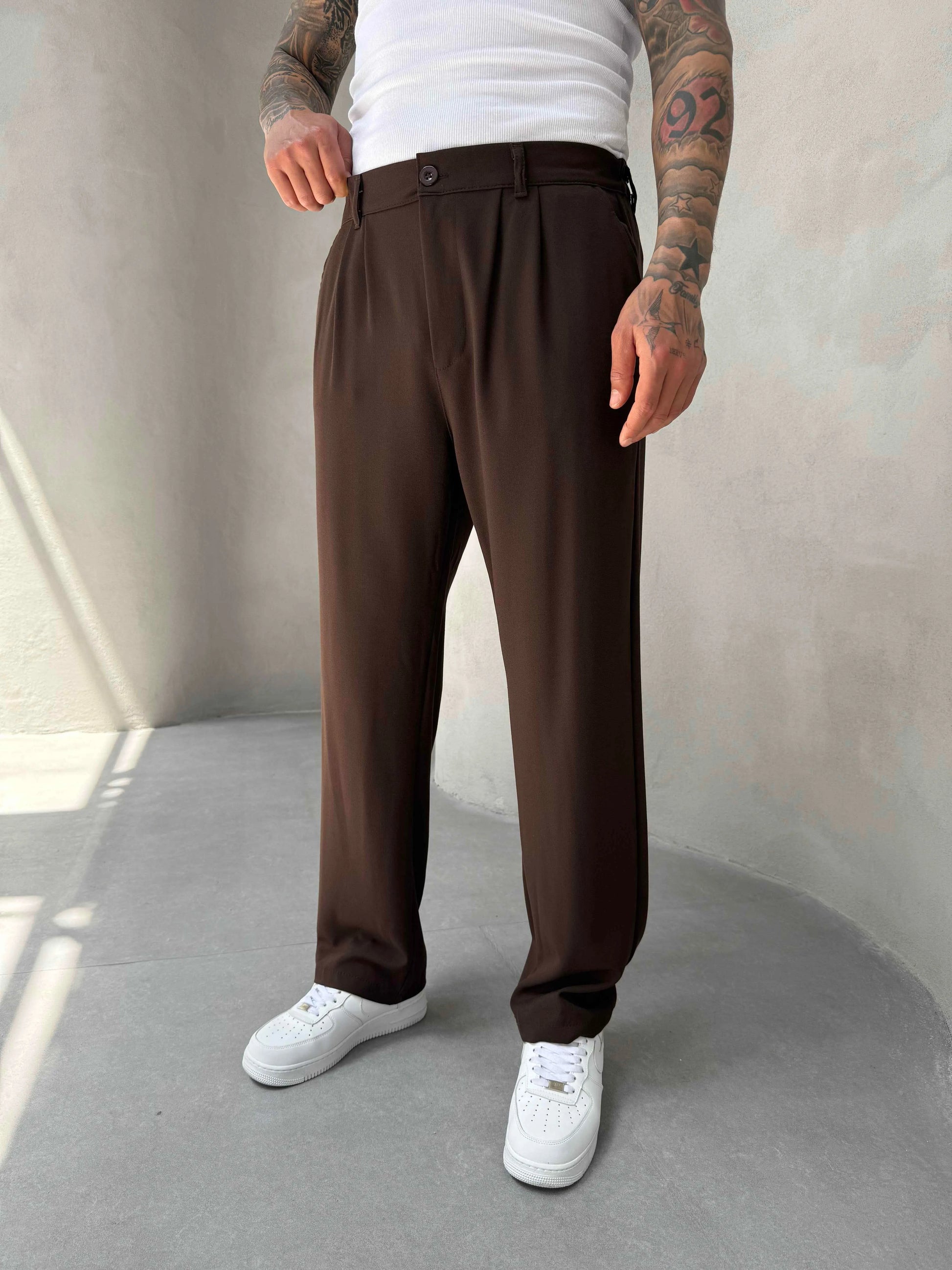 Person wearing brown pleated office pants 