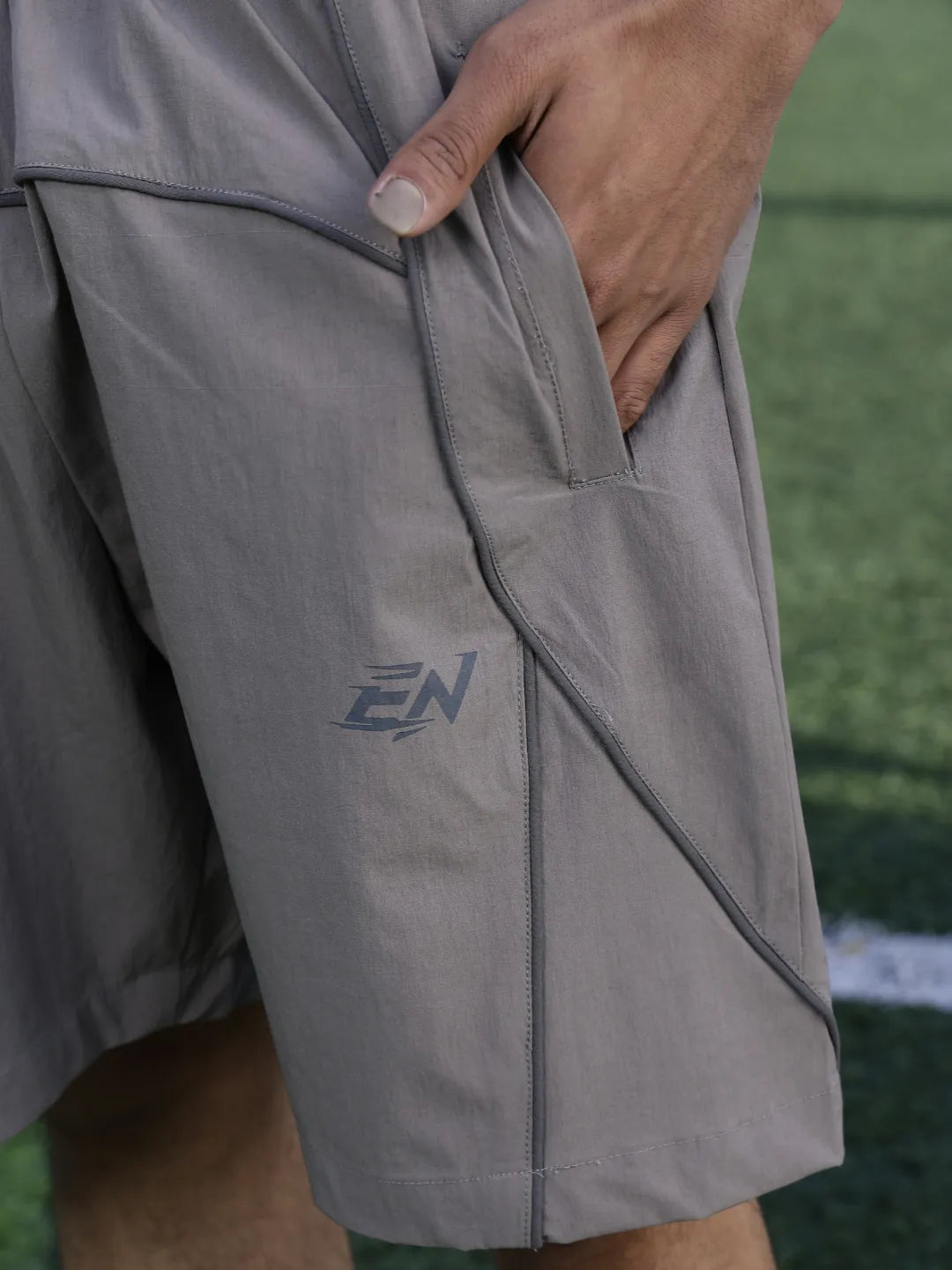 Grey shorts with a logo on the side, worn by a person on a grassy field.