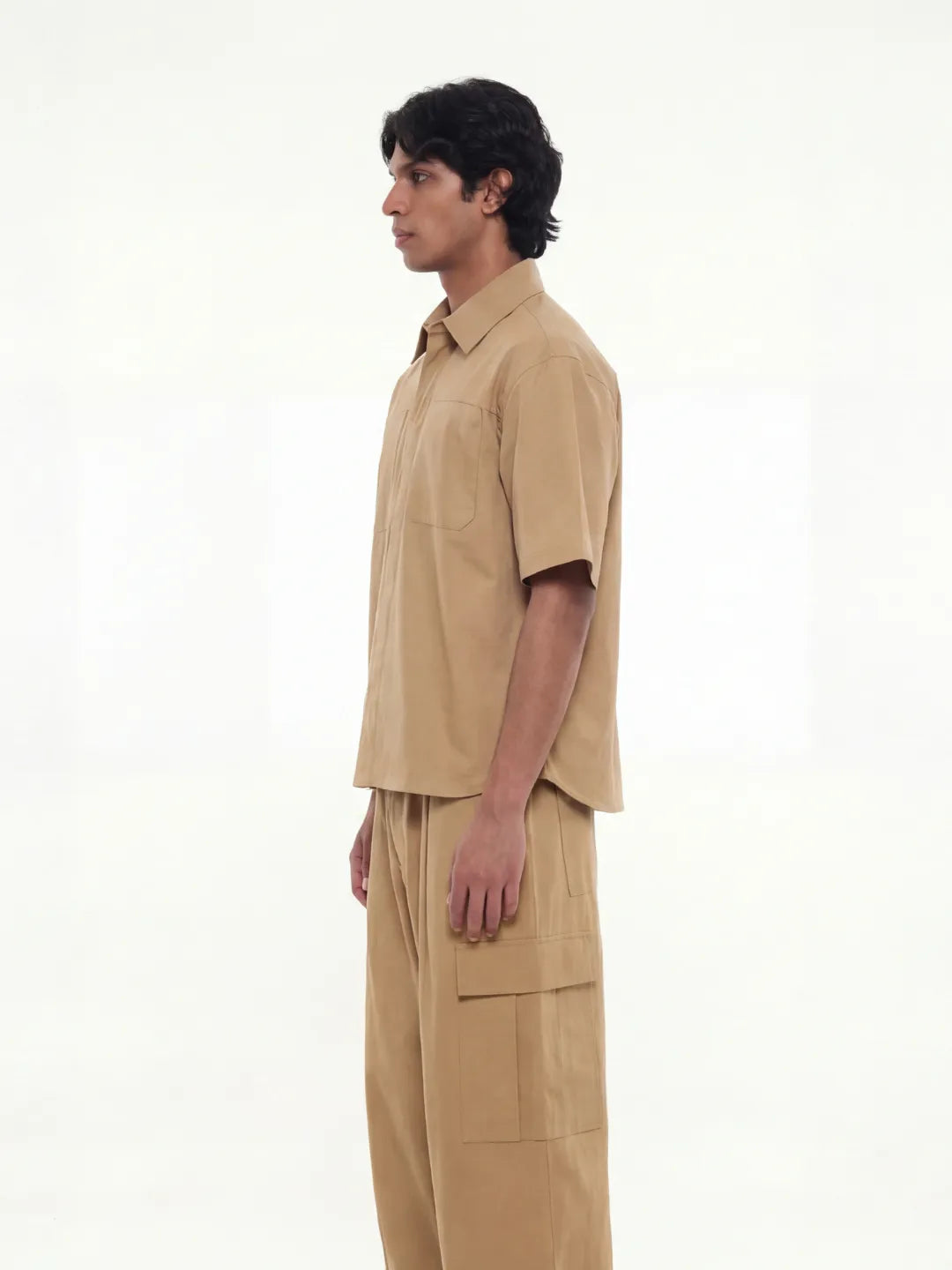 Person wearing a beige outfit on a white background