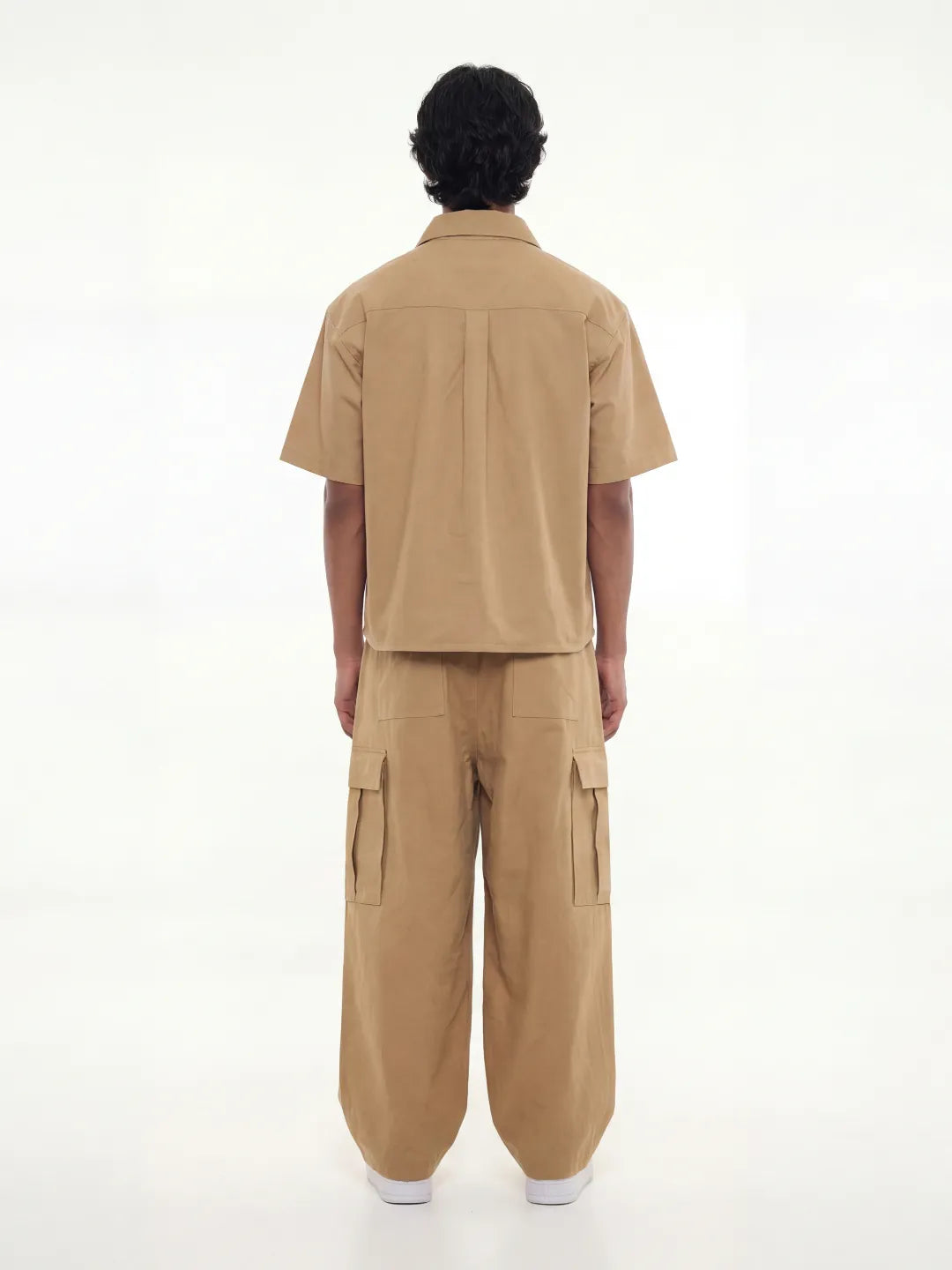 Person wearing a beige shirt with cargo pants on a white background