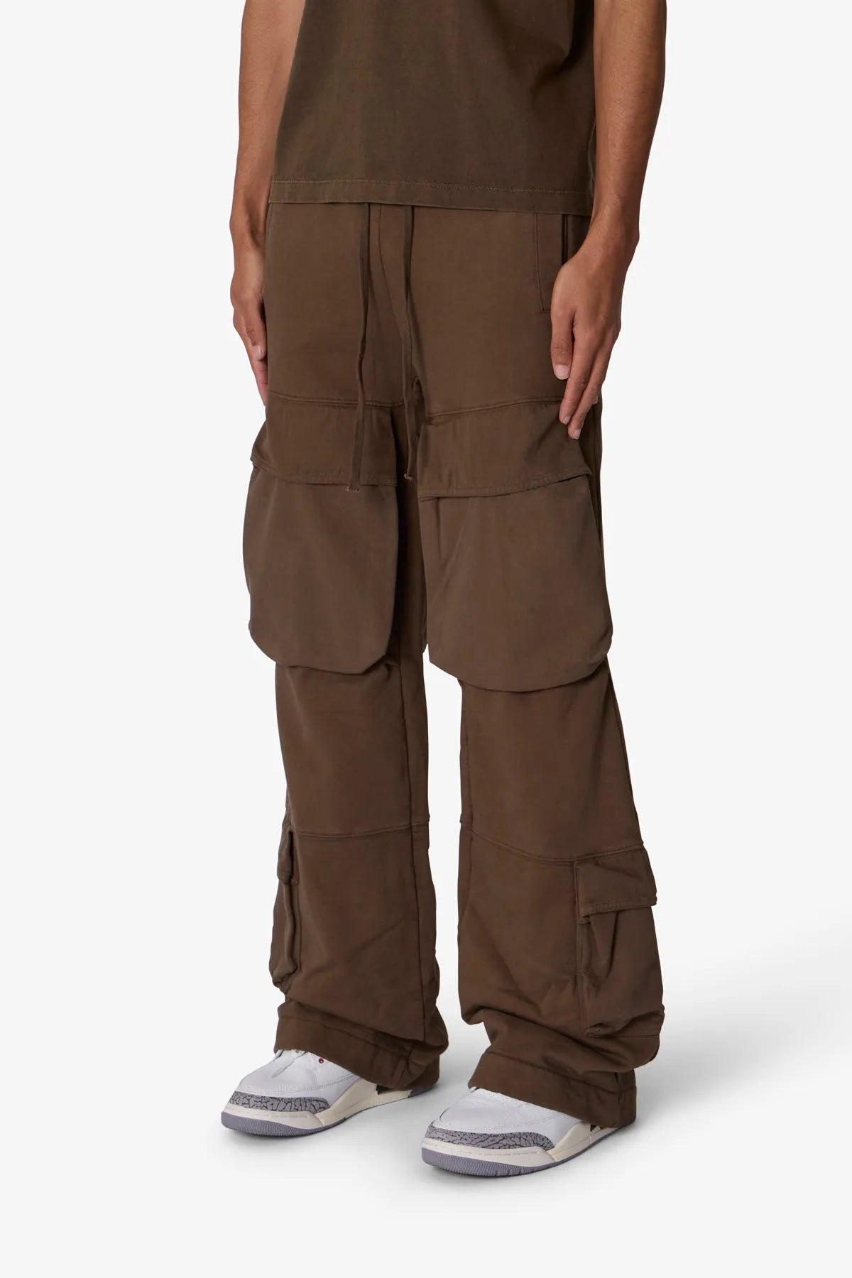 Brown cargo pants worn by a person on a white background