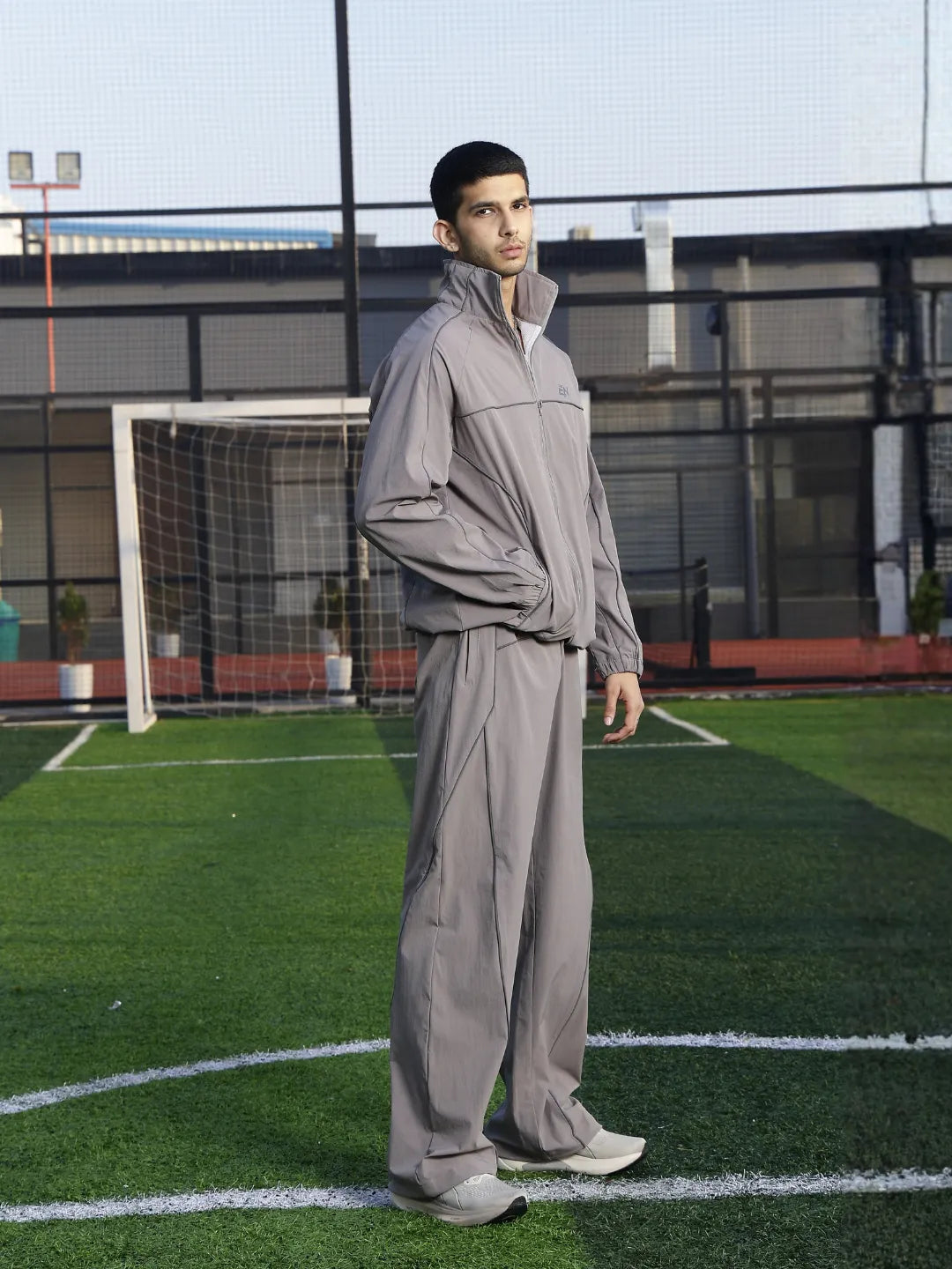 Person wearing a grey tracksuit on a sports field
