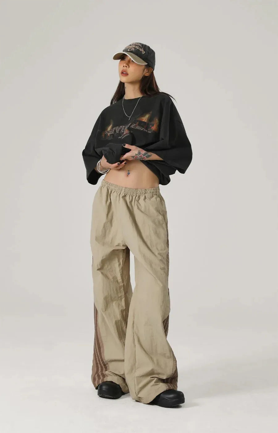 Person wearing a black oversized sweatshirt and beige pants on a white background