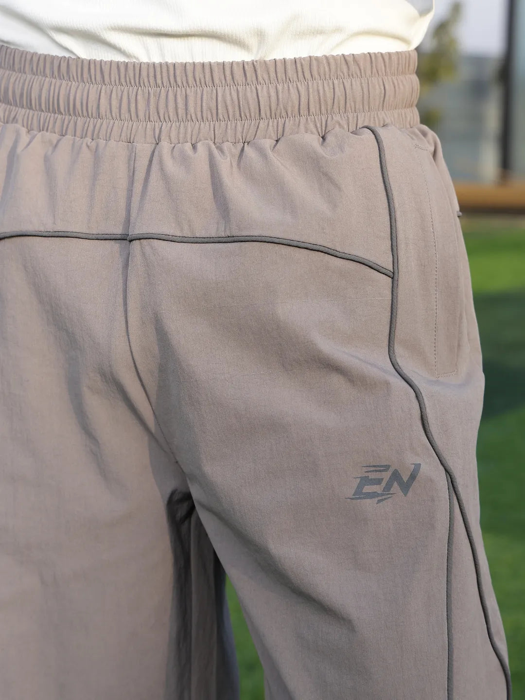 Close-up of grey pants with a logo on a blurred outdoor background