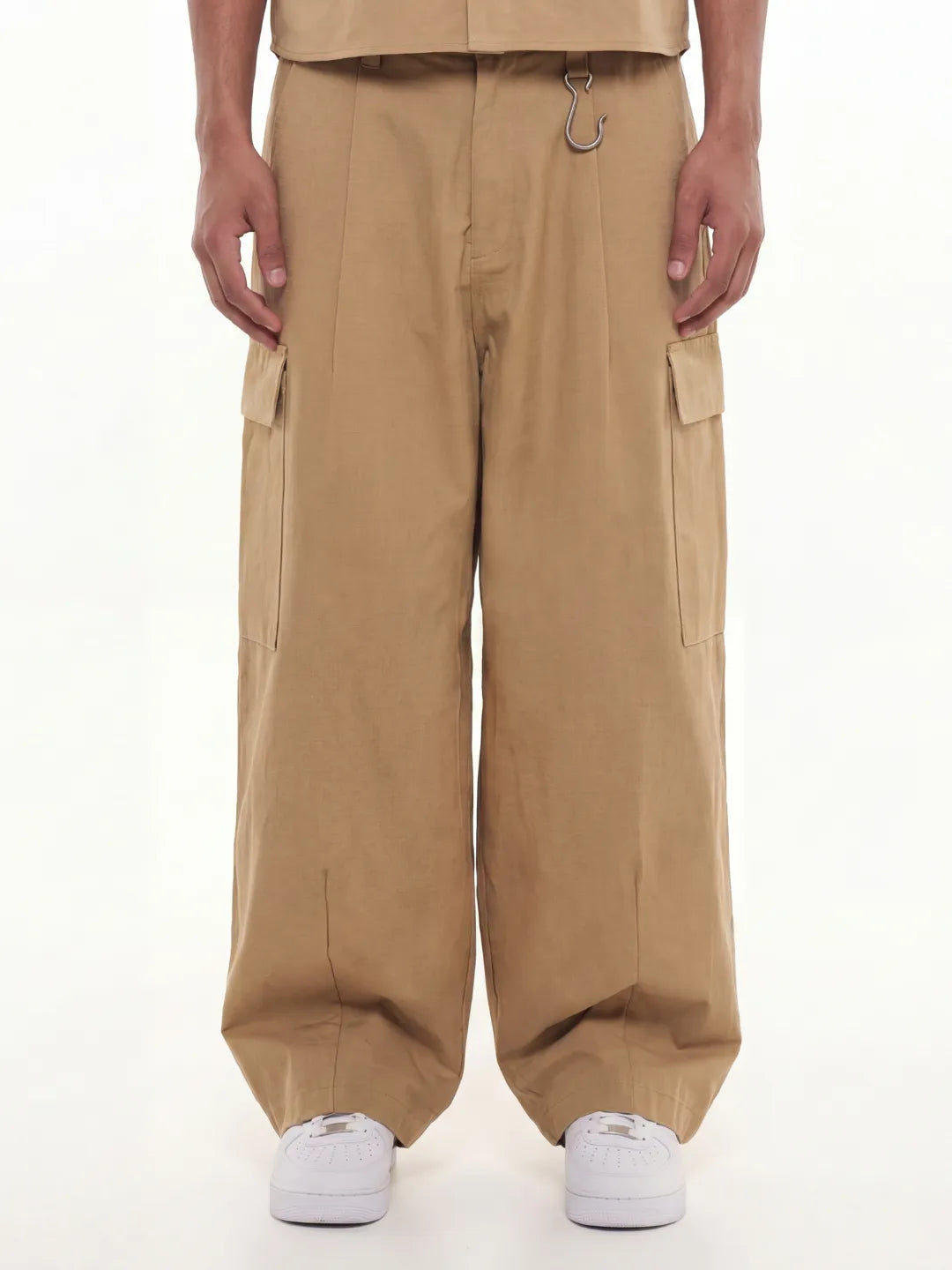 Person wearing beige cargo pants and shirt on a white background