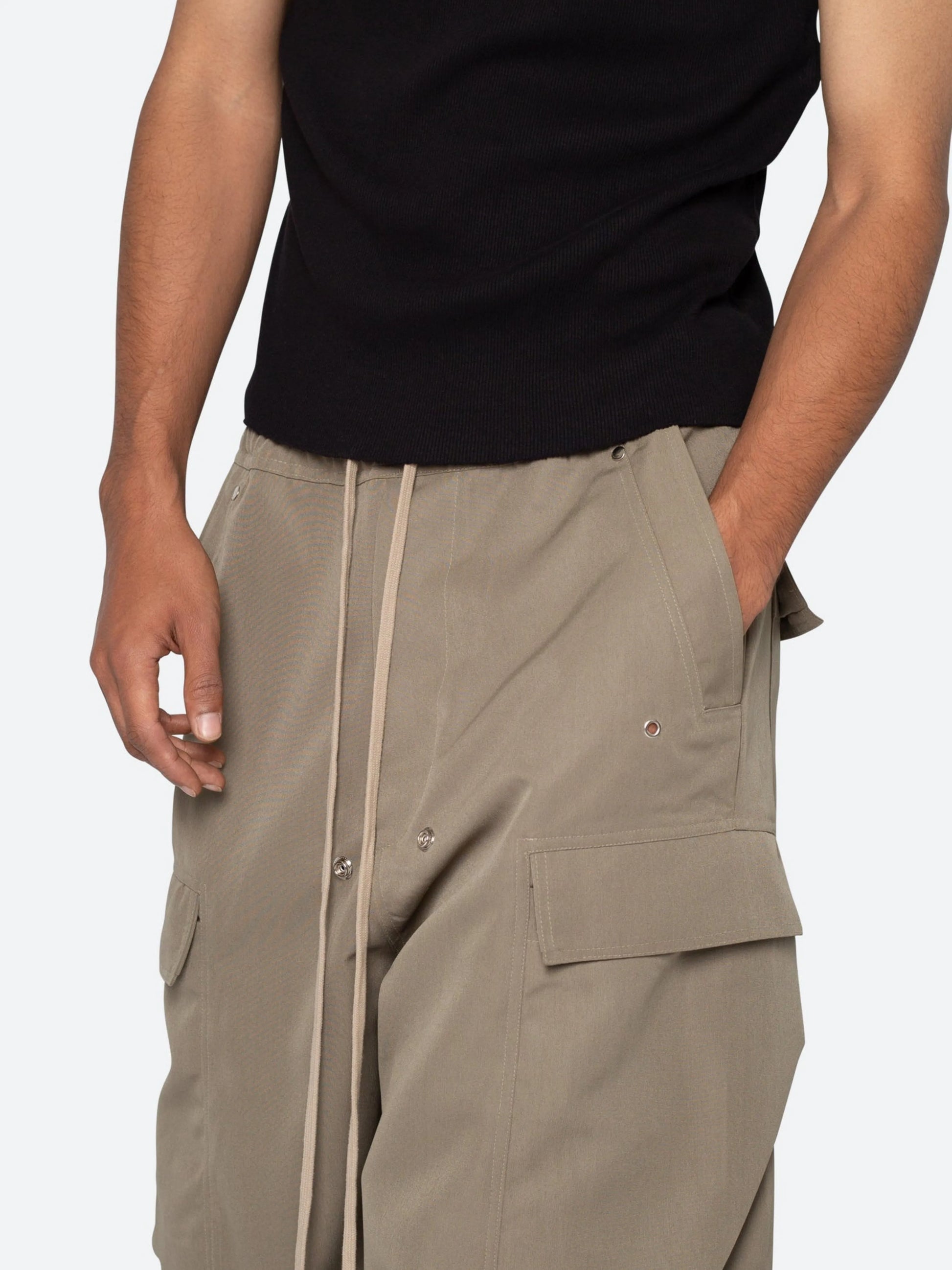 Person wearing beige cargo pants and a black top on a white background