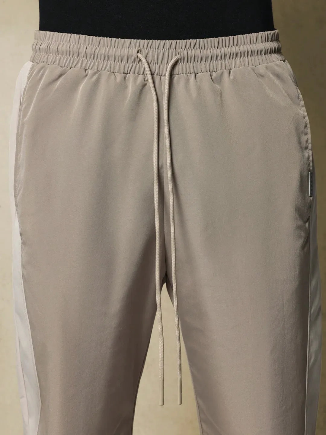 Beige track pants with drawstring on a neutral background