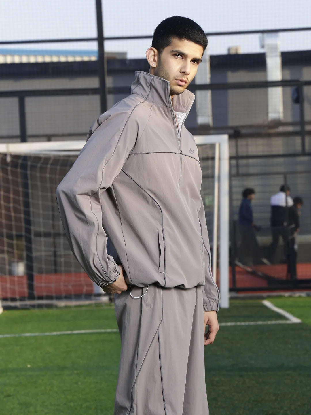Person wearing a grey tracksuit on a sports field with a blurred background