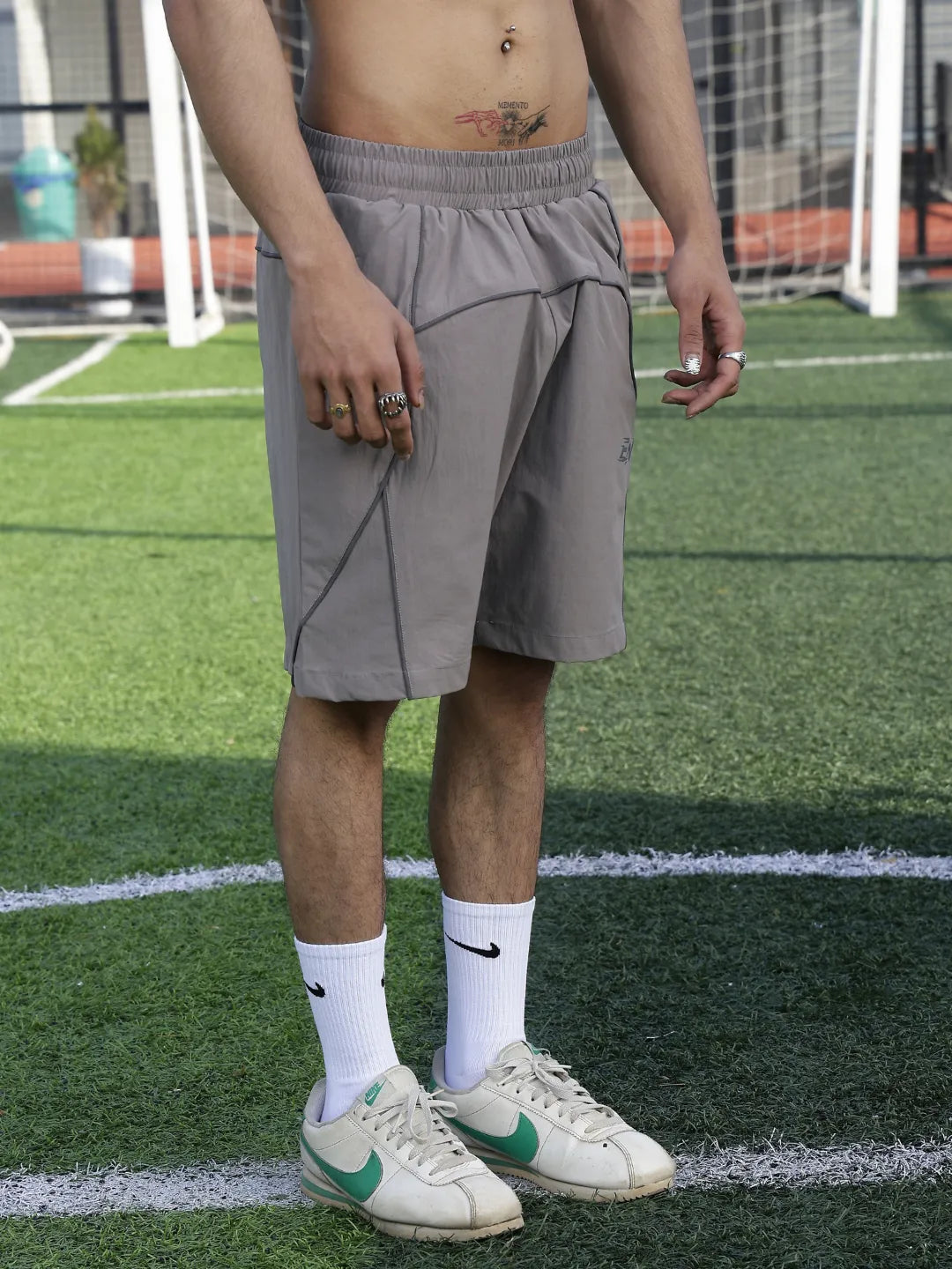 Person wearing grey shorts and white sneakers on a sports field