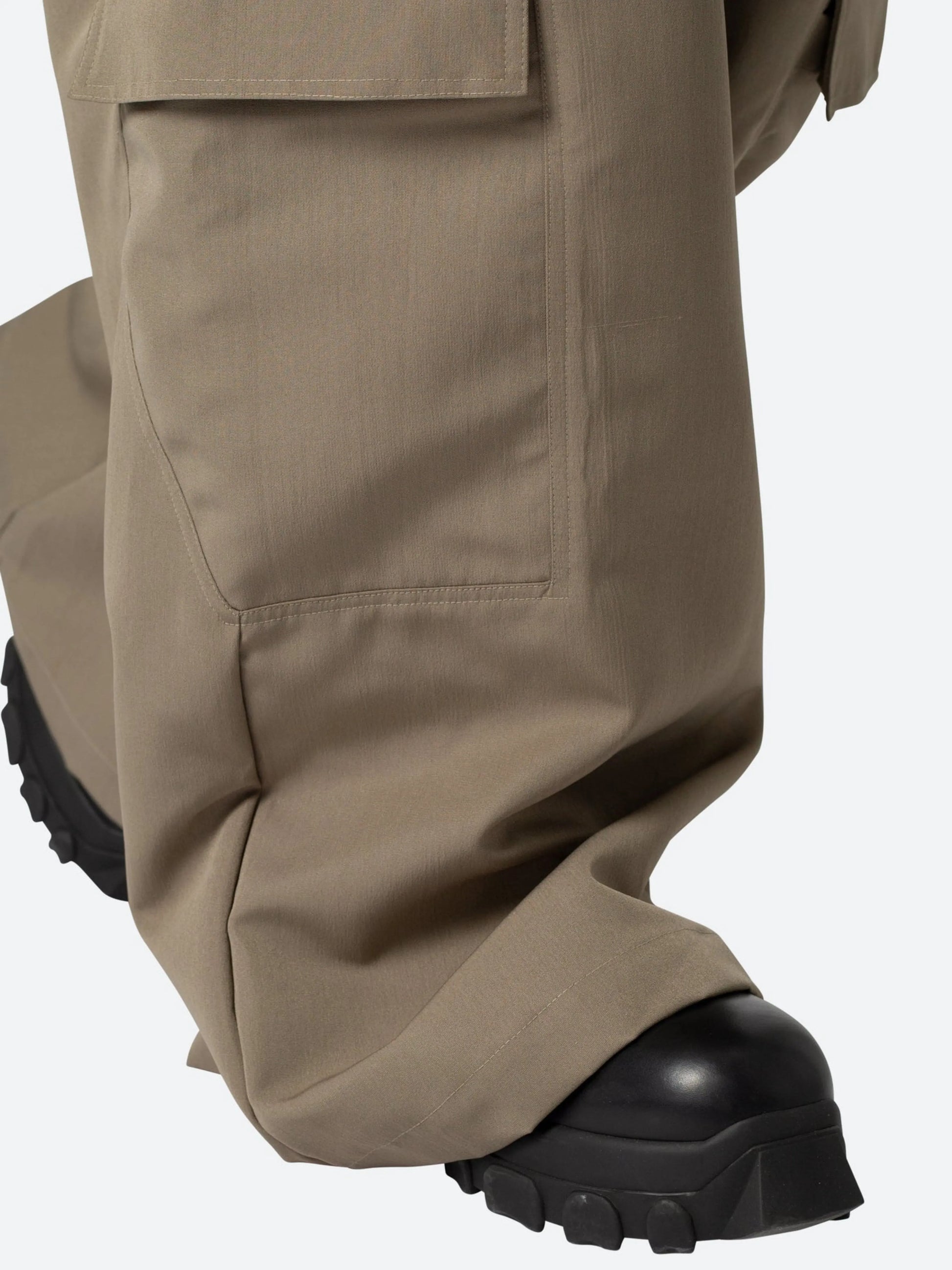 Close-up of beige pants with black boots on a white background