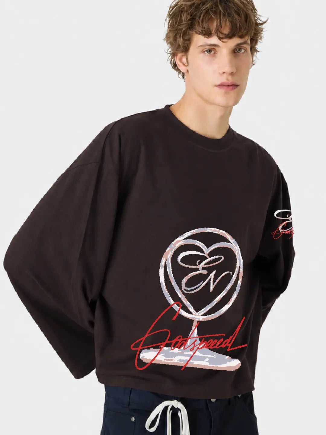 Person wearing a brown oversized t-shirt with a logo and text on a white background