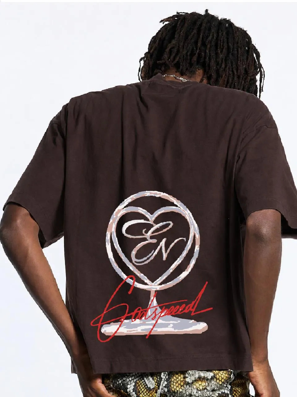Person wearing a brown oversized t-shirt with a logo and text on the back against a white background