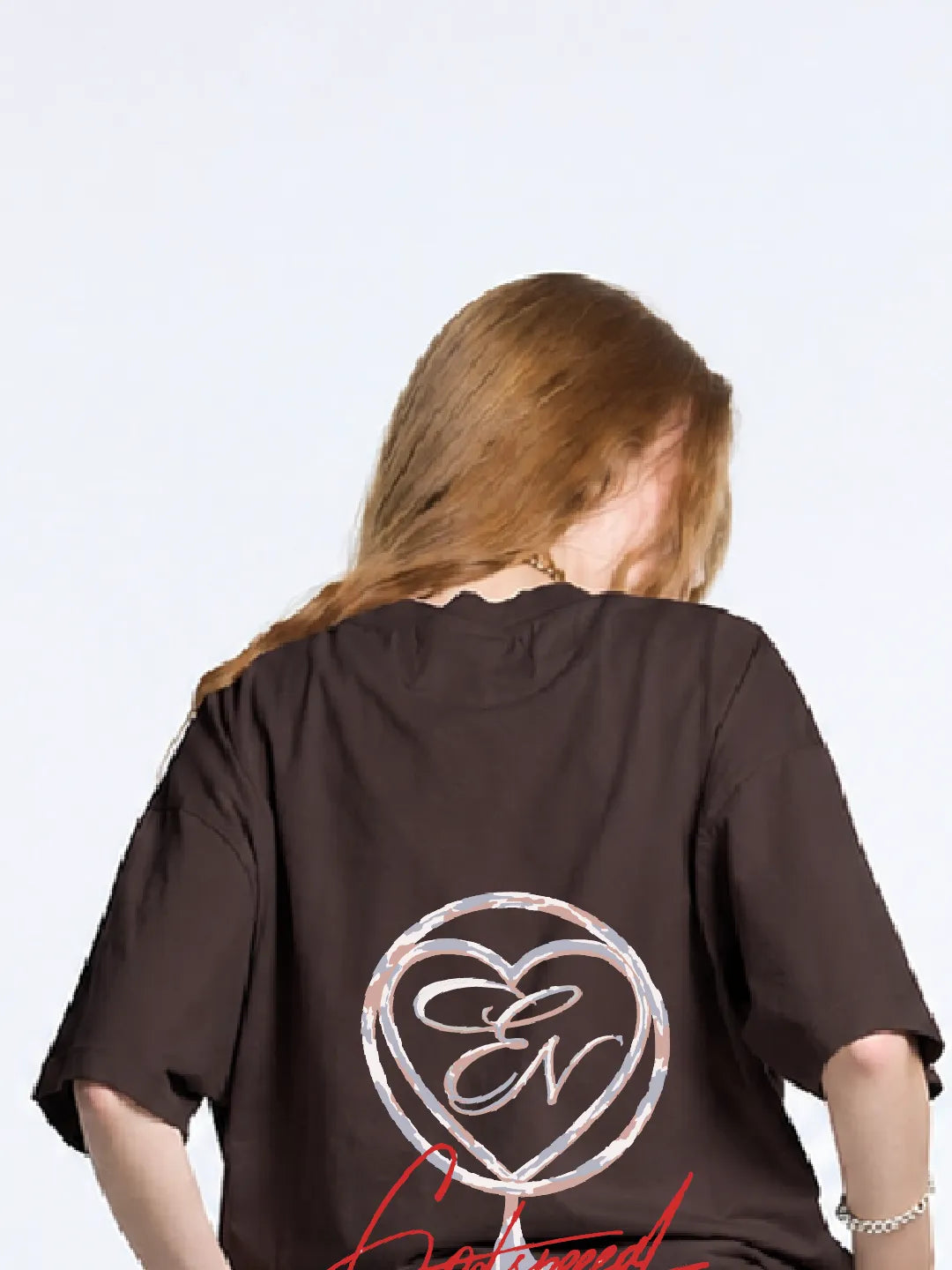Person wearing a brown oversized t-shirt with a logo on the back against a white background