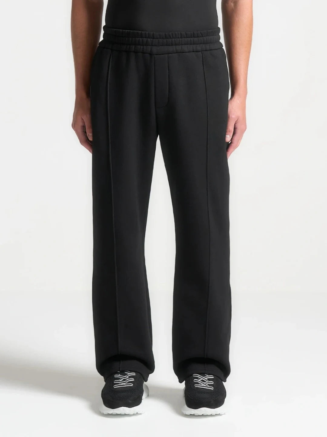 Person wearing black sweatpants with white text on a white background