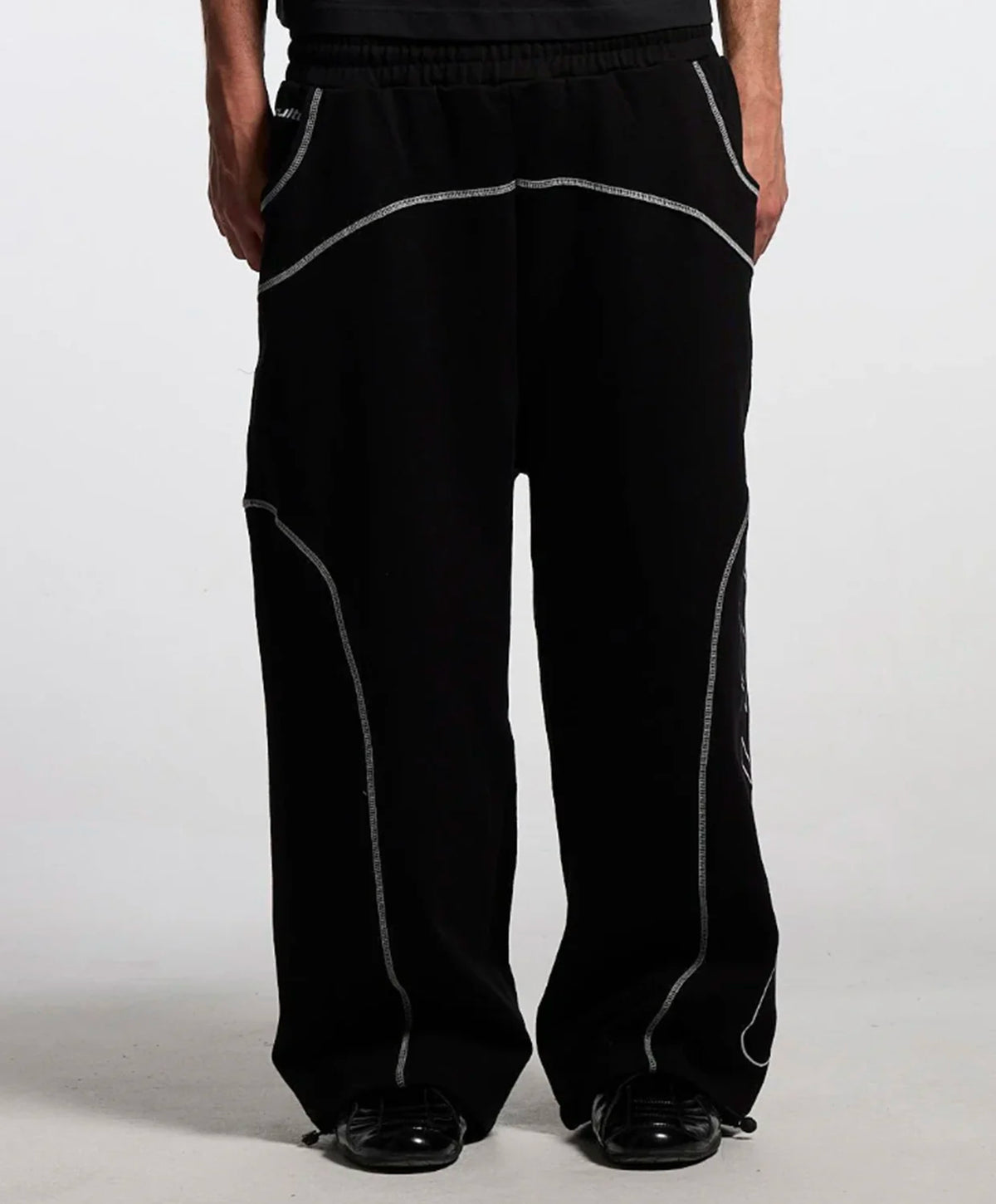 Black wide-leg sweatpants with contrasting light grey stitched paneling, shown on a model from the waist down