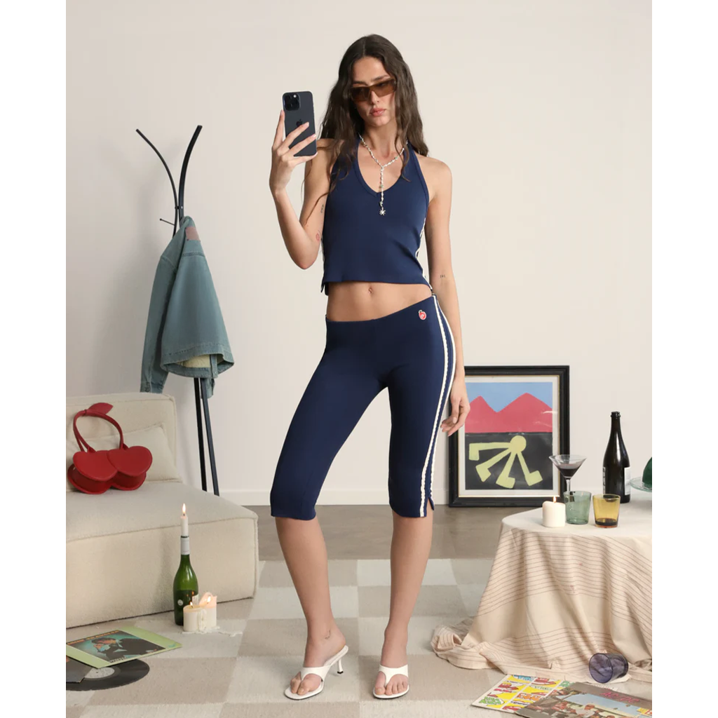 Woman taking a mirror selfie wearing navy athletic wear in a living room.