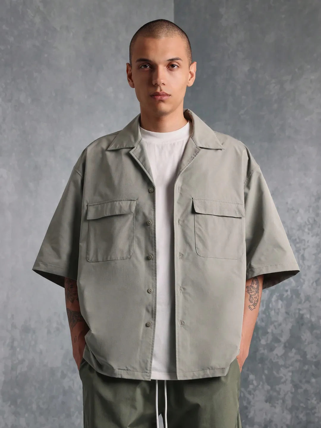 Man wearing a light grey oversized shirt against a grey background