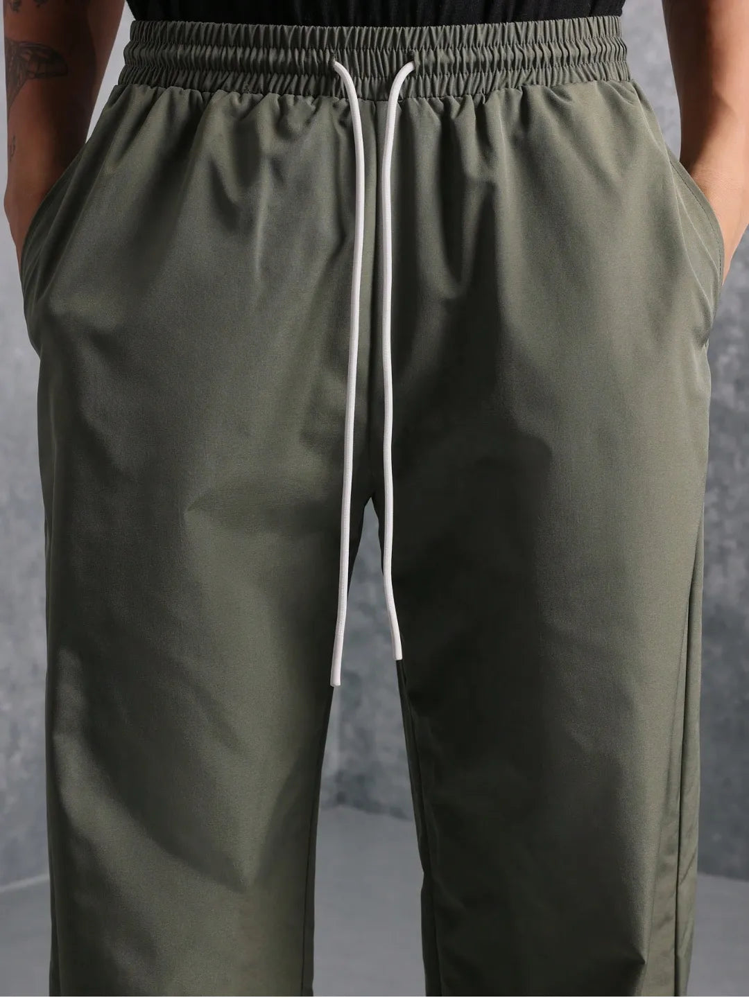 Green pants with a white drawstring on a neutral background