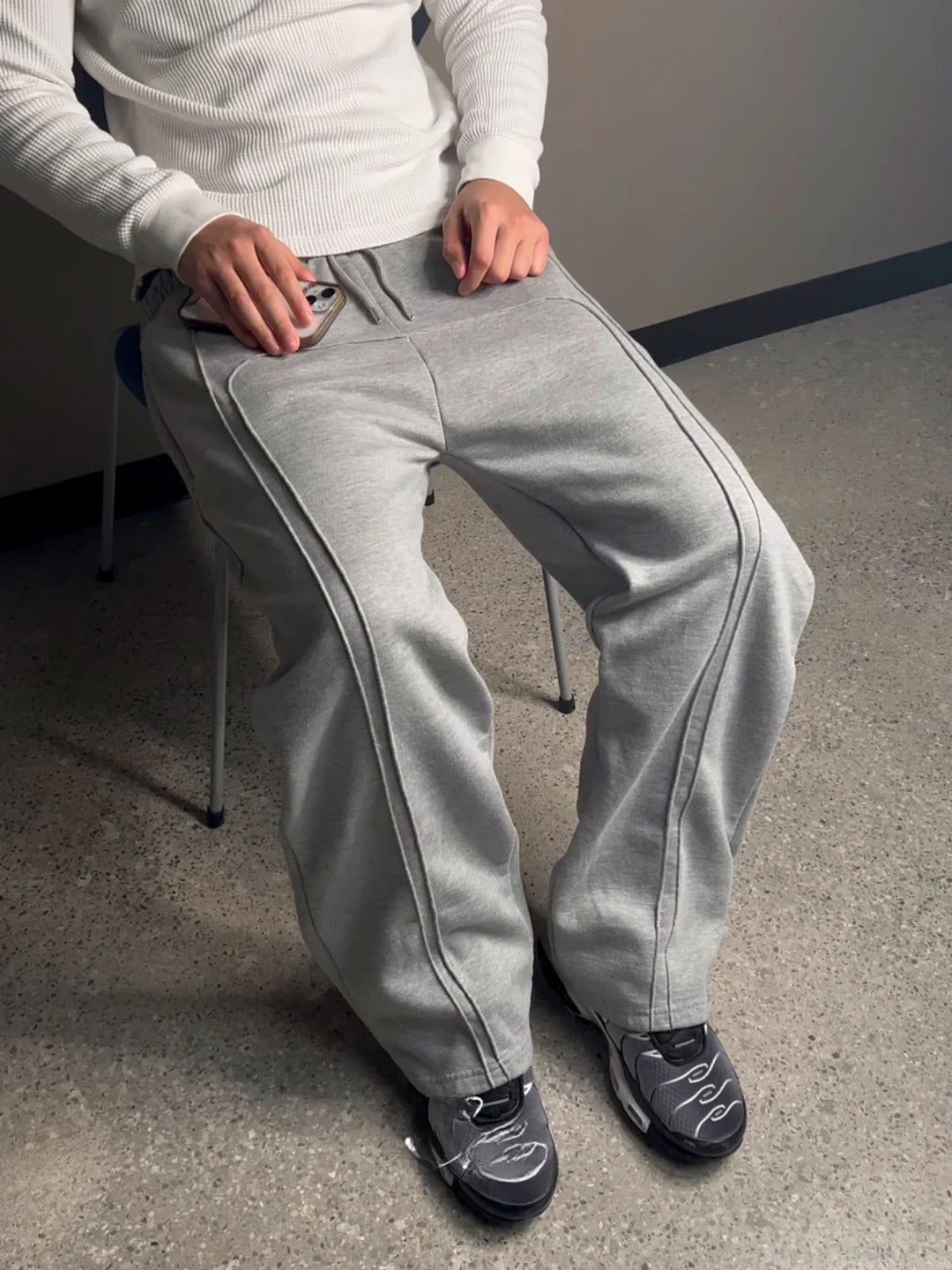 Person wearing grey sweatpants sitting on a chair indoors.