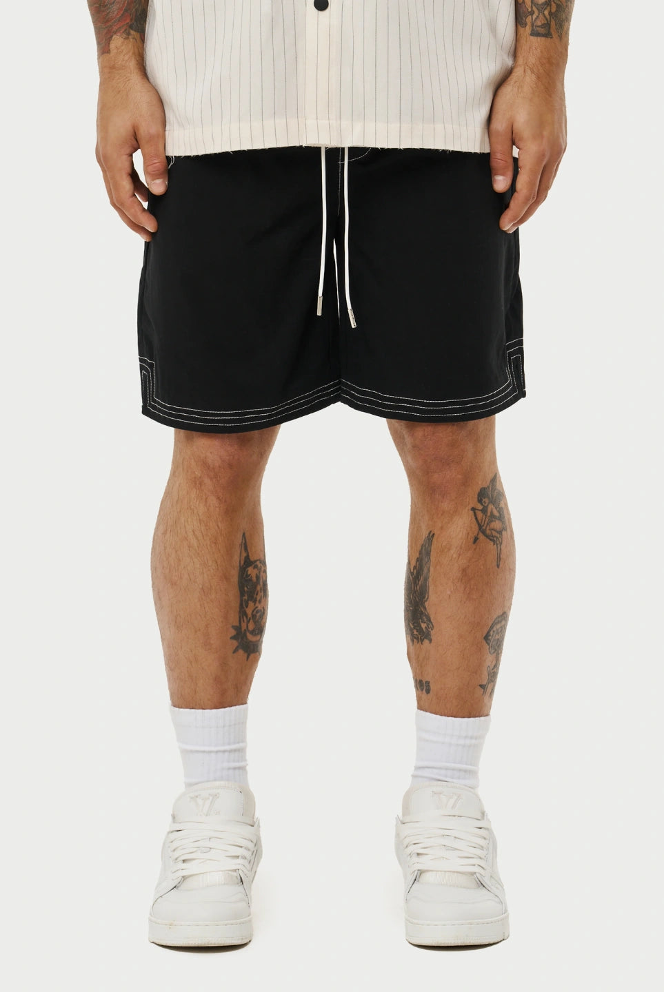 Person wearing black shorts with white trim on a plain background