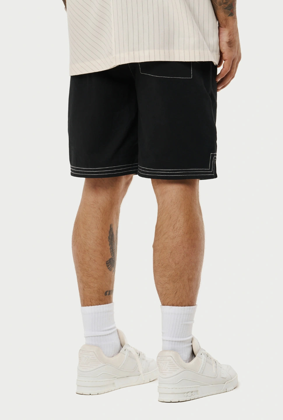 Person wearing black shorts with white trim on a plain background