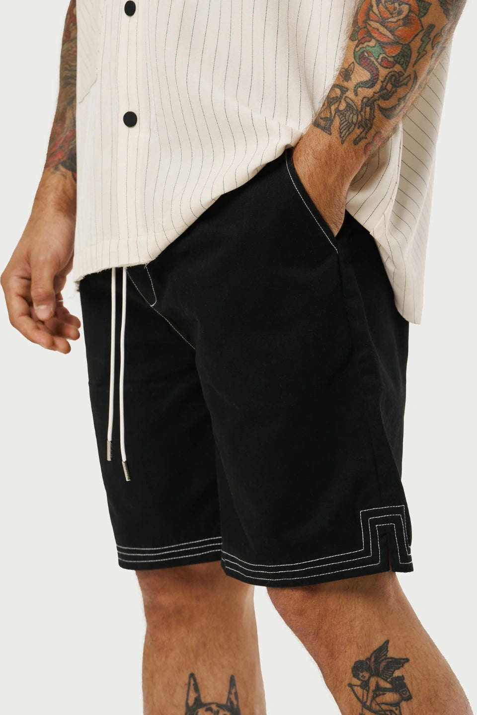 Person wearing black shorts with white trim on a plain background