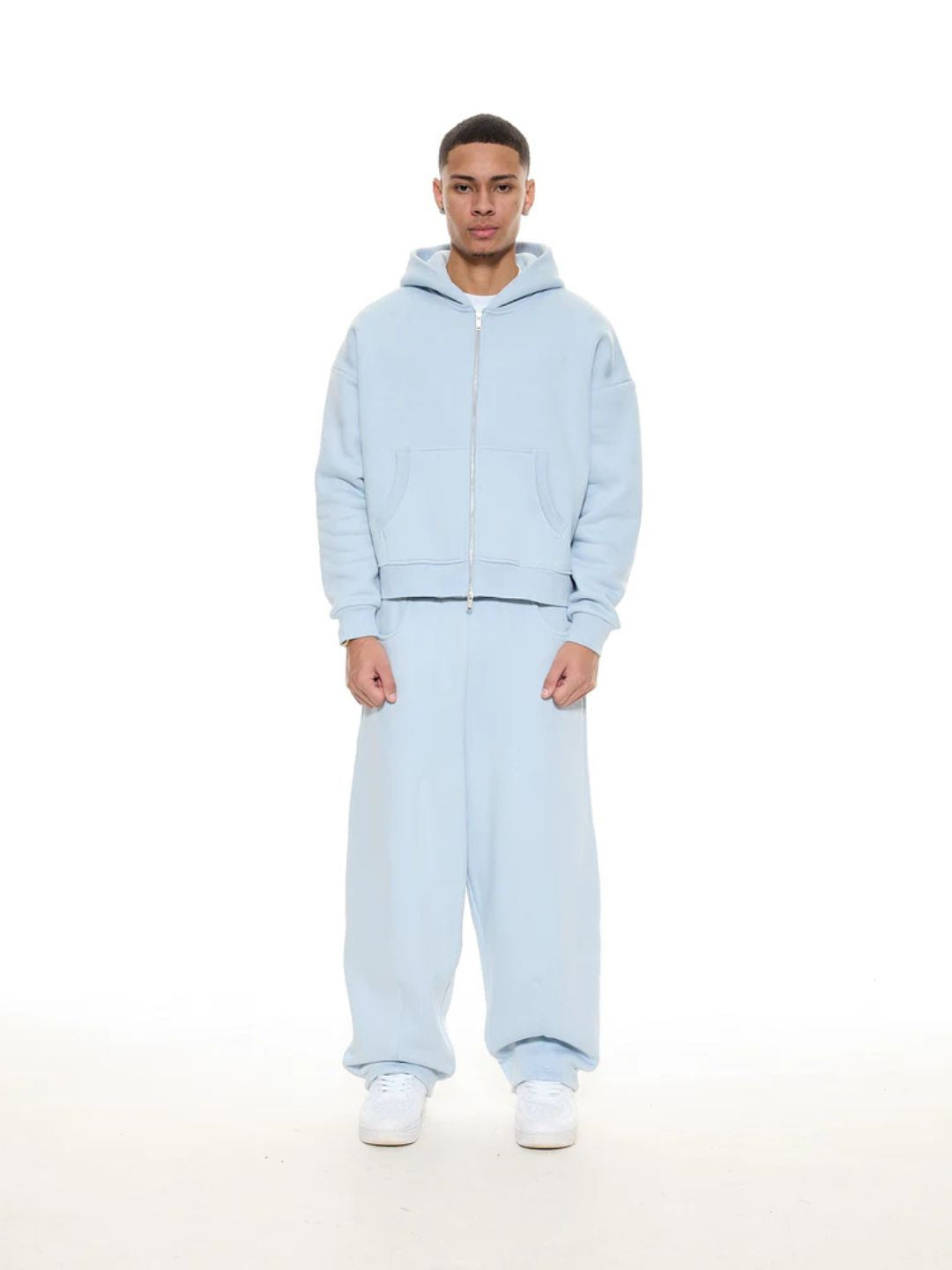 Person wearing a light blue tracksuit on a white background