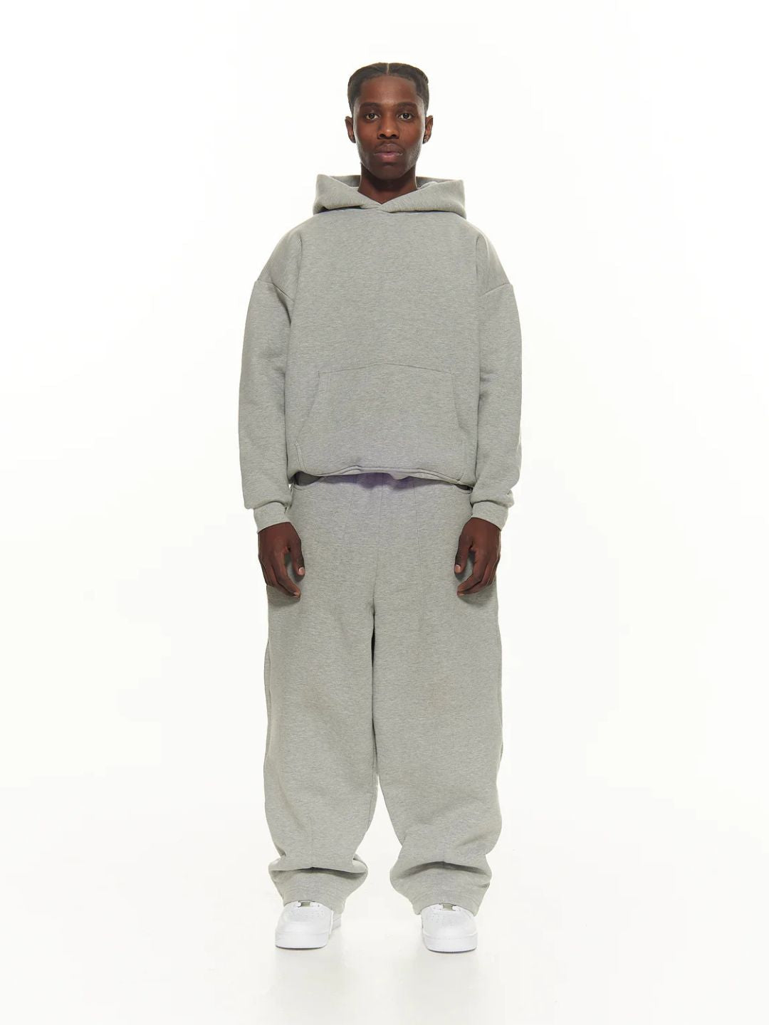 Person wearing a grey hoodie and sweatpants on a white background