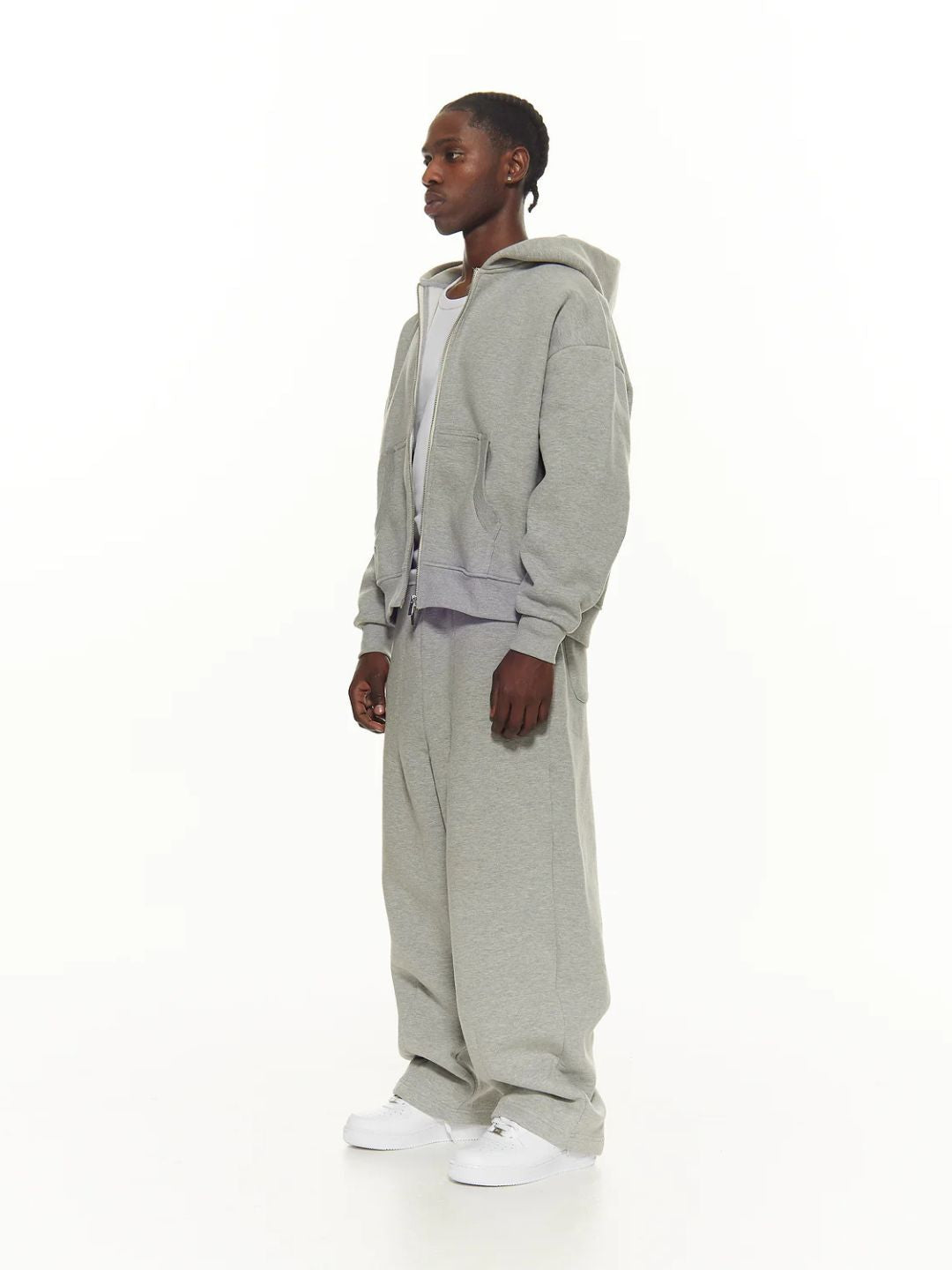 Person wearing a grey hoodie and pants on a white background