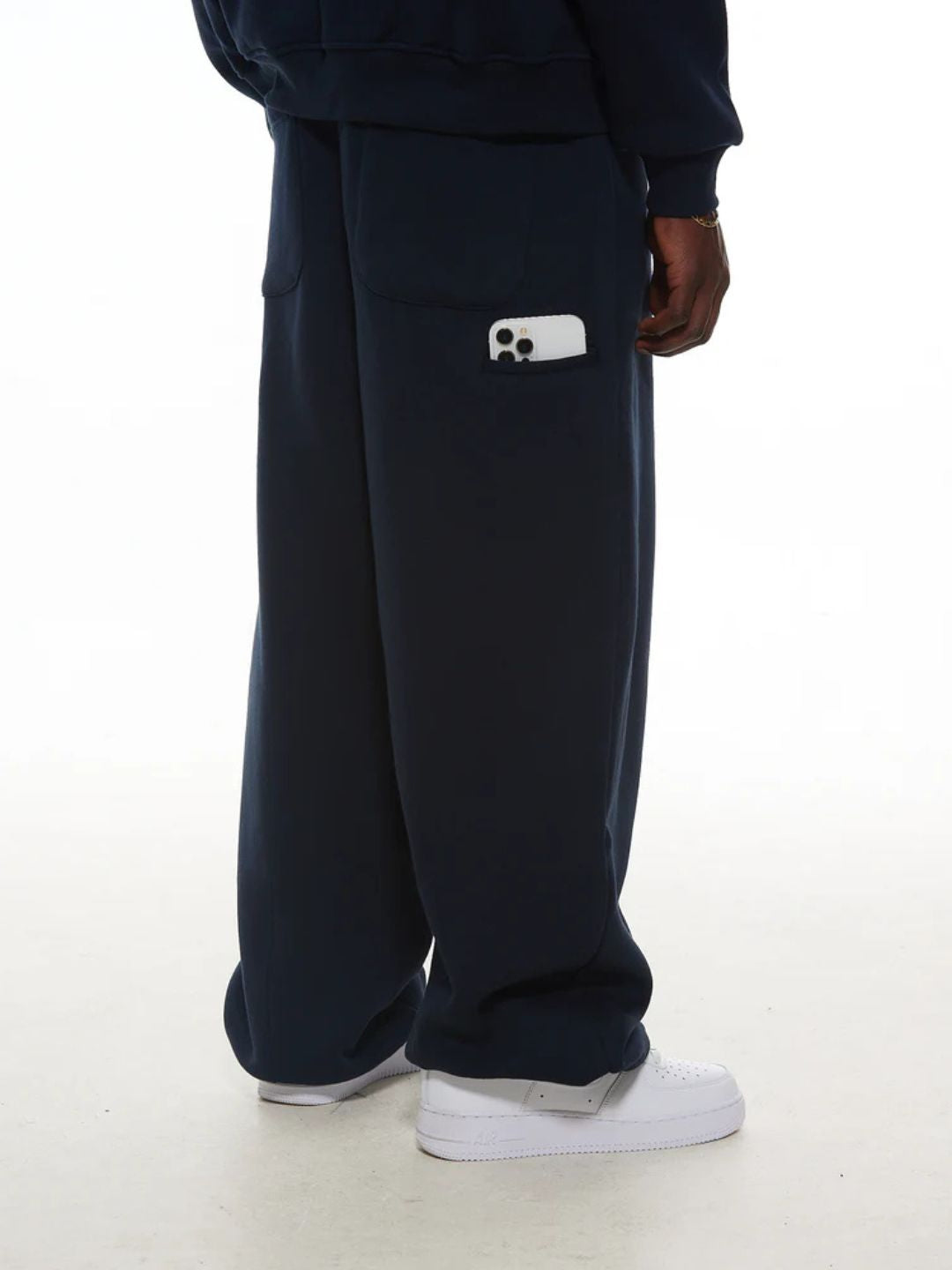 Navy blue sweatpants with a small white logo on a white background
