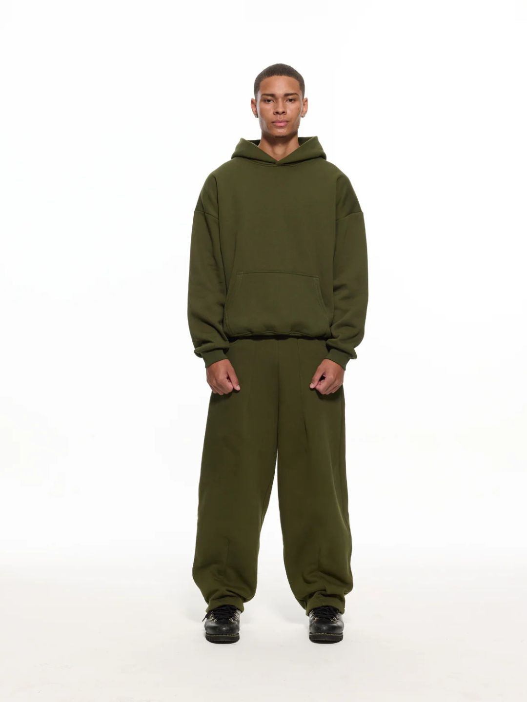 Person wearing a green hoodie and sweatpants on a white background